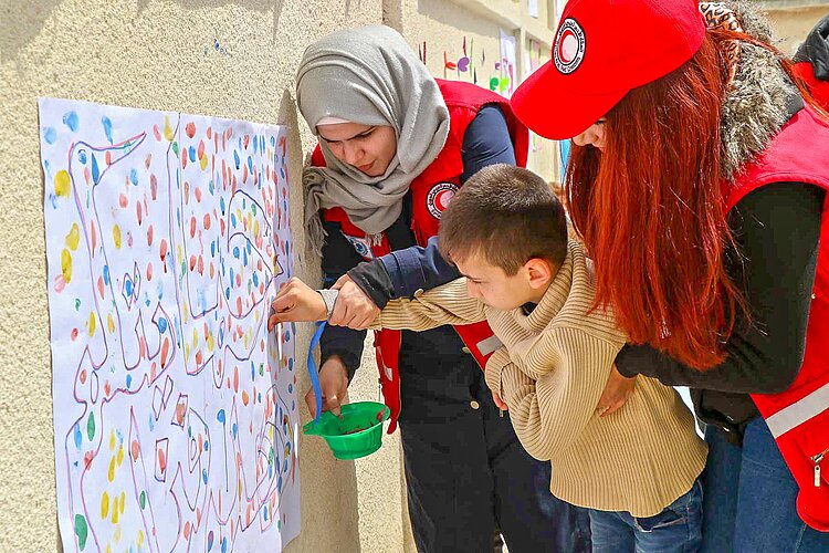 Voluneers finger painting with children