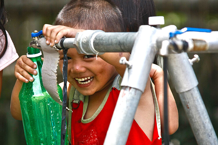 Philippinen: Trinkwasseranlage Lachender Junge mit Flasche an Wasserhahn