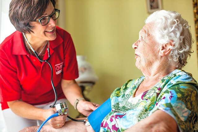 DRK-Fachkraft misst Blutdruck bei Seniorin