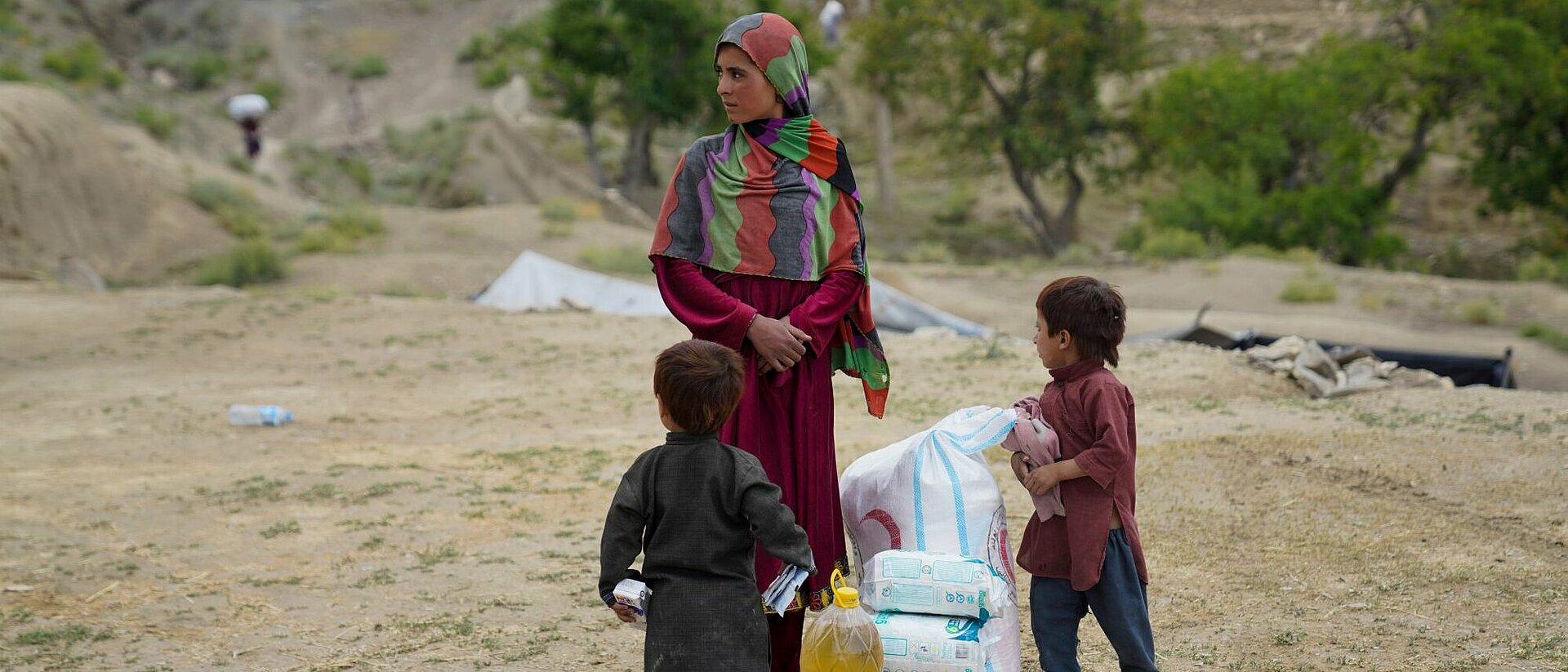 Humanitäre Hilfe in Afghanistan Frau mit zwei Kindern und Hilfsgütern in Afghanistan