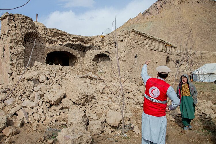 Humanitäre Hilfe in Afghanistan Helfer des Afghanischen Roten Halbmondes spricht mit einem Jungen