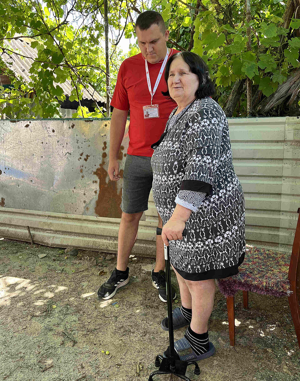 Gehversuche mit den Physiotherapeuten vom Ukrainischen Roten Kreuz Ein Rotkreuzmitarbeiter hilft einer Frau mit einer Gehhilfe