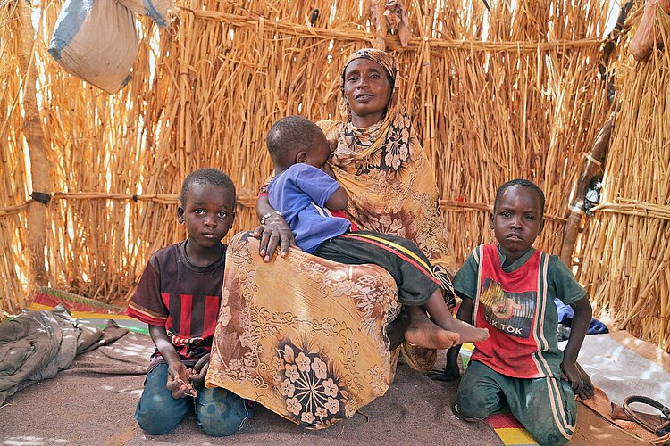 Frau mit Kindern in Hütte aus Maishalmen