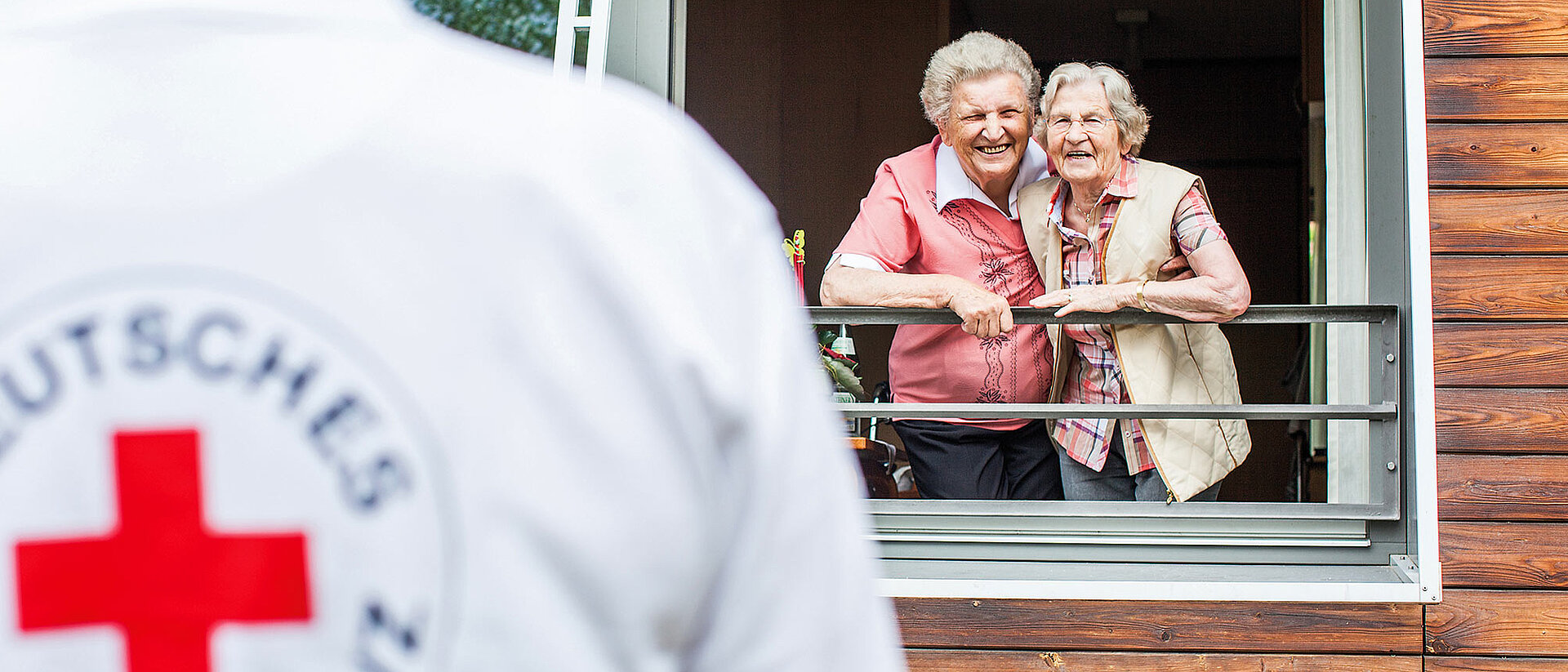 Seniorinnen am Fenster und Pflegekraft