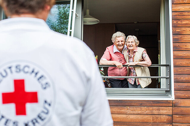 Seniorinnen am Fenster und Pflegekraft