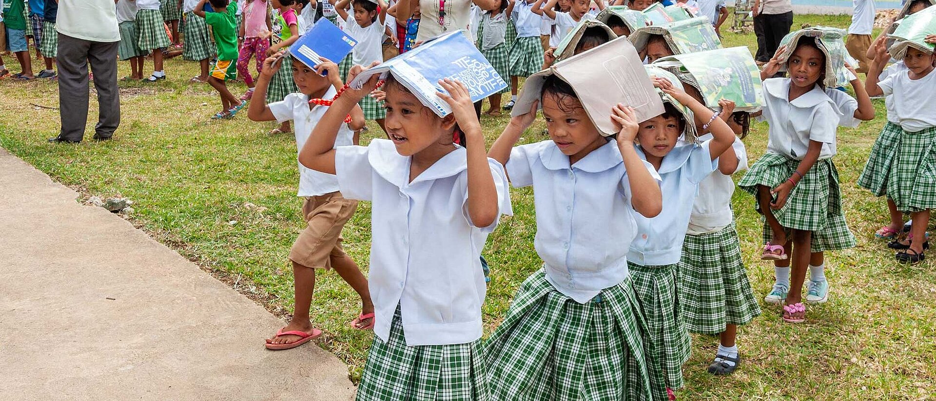 Philippinen: Katastrophenschutzübung Kinder schützen ihre Köpfe mit Schulheften