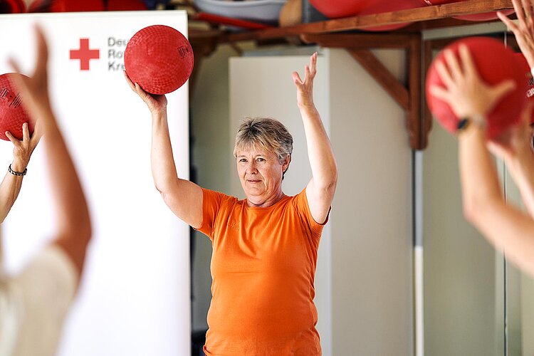 Frau hebt Ball über ihren Kopf