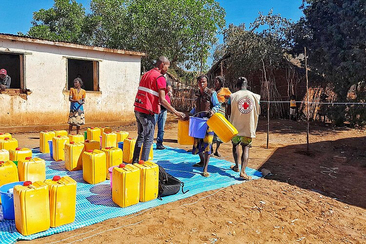 Hilfsgüterverteilung Frau erhält Wasserkanister von Rotkreuzler