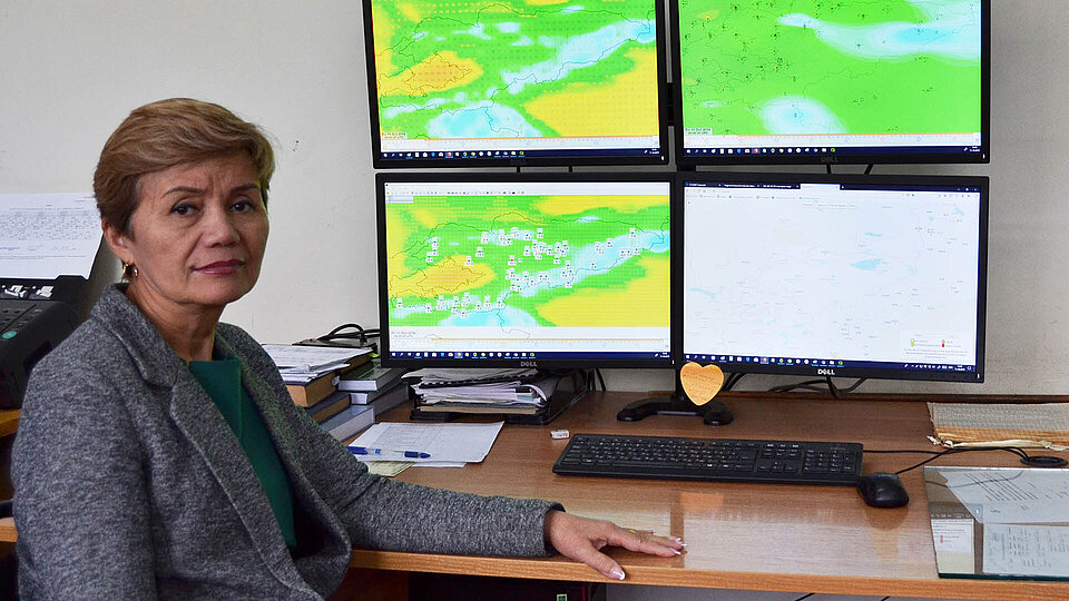 Frau am Schreibtisch mit vier Bildschirmen