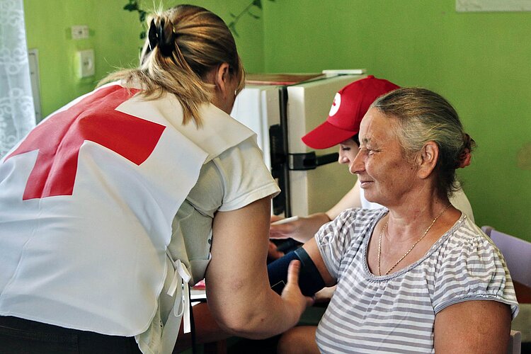 Rotkreuzlerin misst Blutdruck bei Seniorin