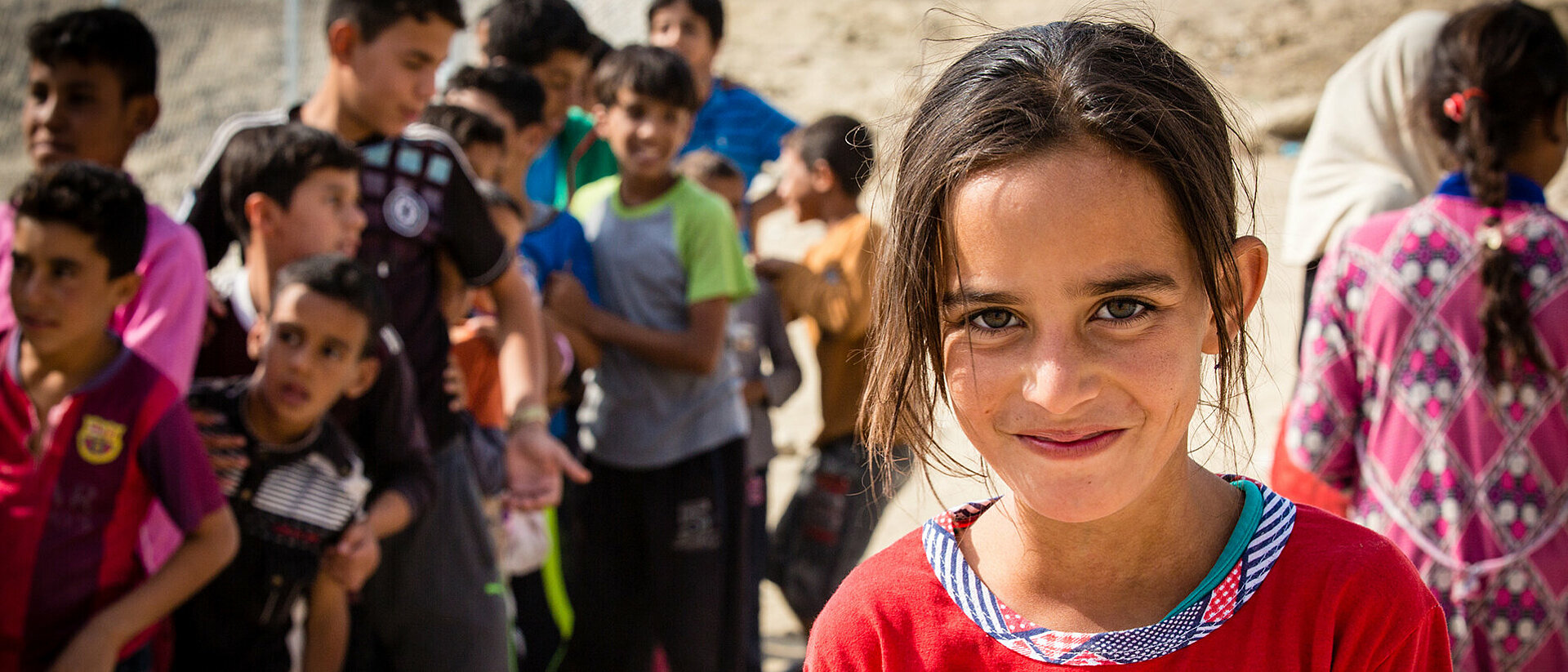 Hilfe für Kinder im Irak lächelndes Mädchen im Irak vor Kindergruppe