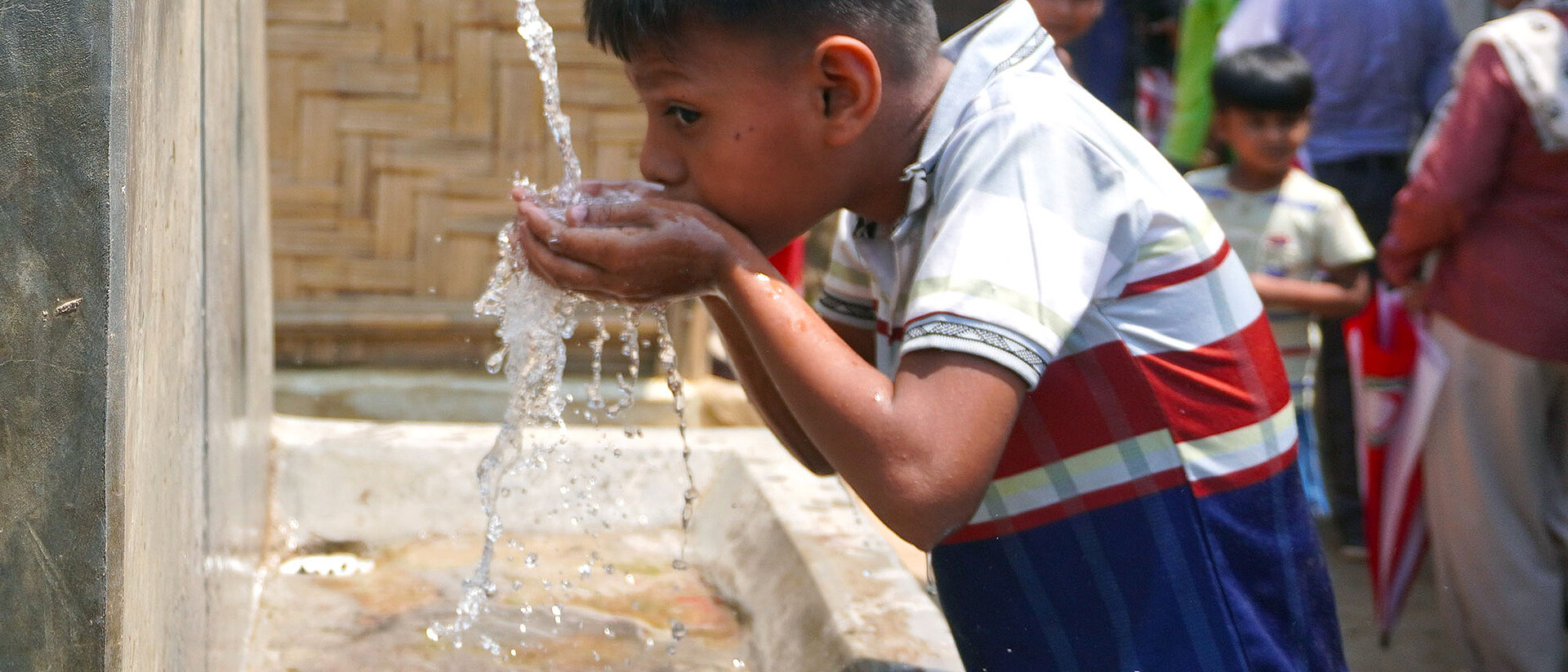 Junge trinkt an Wasserstelle