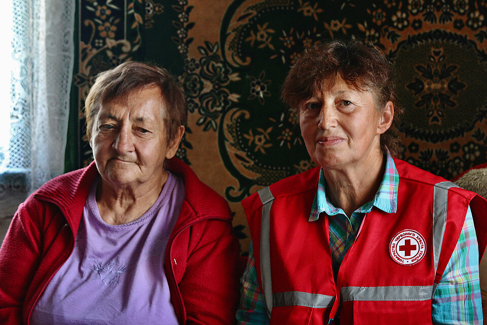 Eine alte Dame und eine Mitarbeiterin des Ukrainischen Roten Kreuzes