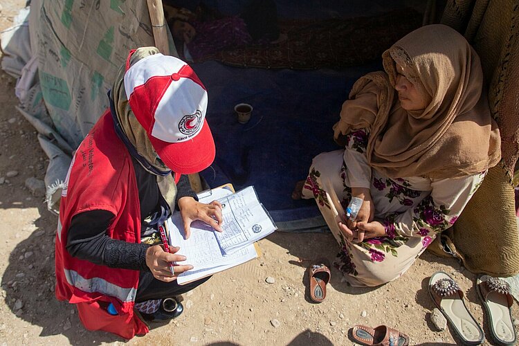 Humanitäre Hilfe in Afghanistan Helferin des Afghanischen Roten Halbmondes spricht mit einer Frau