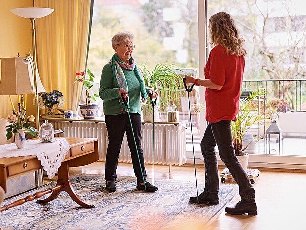 Seniorin und DRKlerin bei Gymnastik mit Expander