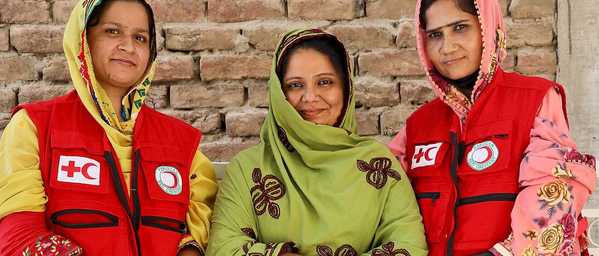 Freiwilligentraining in Pakistan Drei pakistanische Frauen - zwei in Rothalbmond-Kleidung