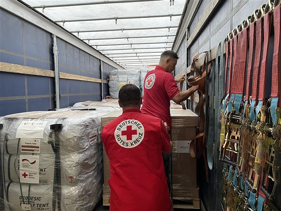 Transport von Hilfsgütern des DRK nach Afghanistan nach schwerem Erdbeben Zwei Männer umgeben von Hilfsgütern