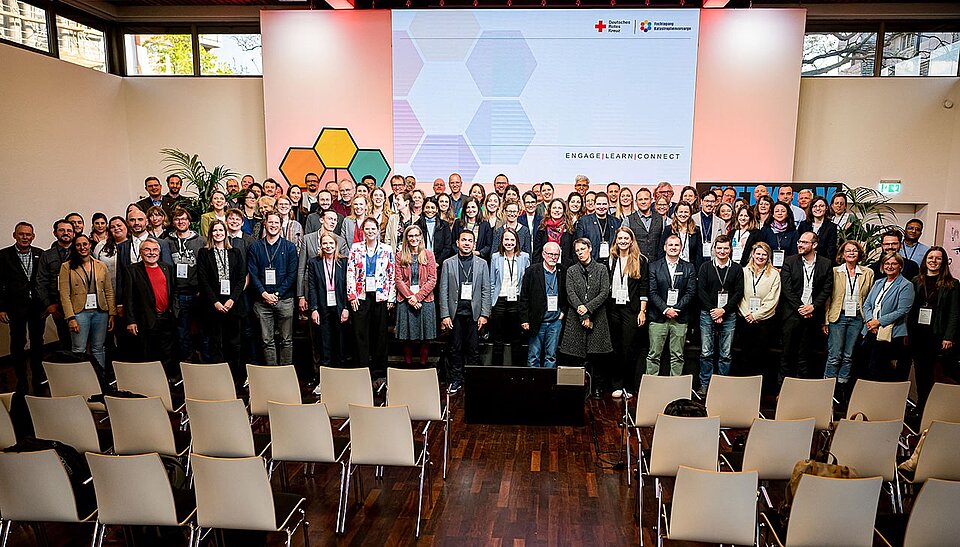 Gruppenfoto_Fachtagung_Katastrophenvorsorge Auf einem Podium stehen viele Menschen