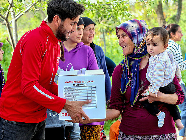 Volunteer handing over a box to woman